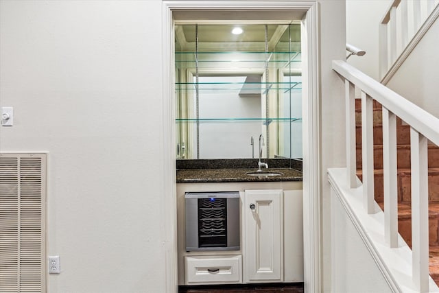 bar with indoor wet bar, a heating unit, a sink, beverage cooler, and stairs