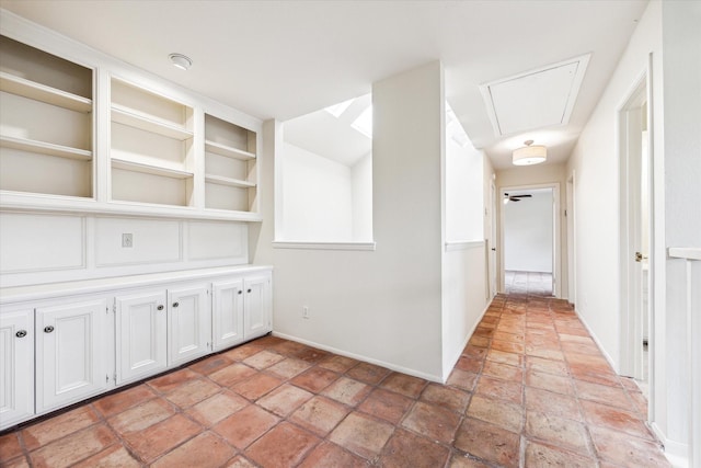 hallway featuring attic access and stone finish flooring