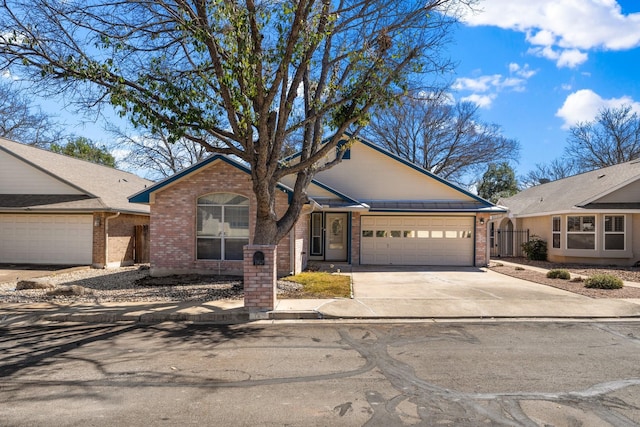 single story home with driveway, brick siding, and an attached garage