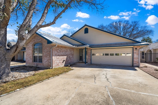 single story home with metal roof, an attached garage, brick siding, concrete driveway, and a standing seam roof