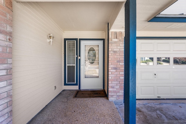 entrance to property with a garage and brick siding