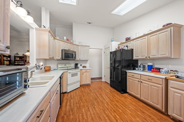 kitchen featuring white range with electric cooktop, a sink, black fridge with ice dispenser, light countertops, and stainless steel microwave