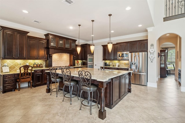 kitchen with arched walkways, dark brown cabinets, appliances with stainless steel finishes, and visible vents