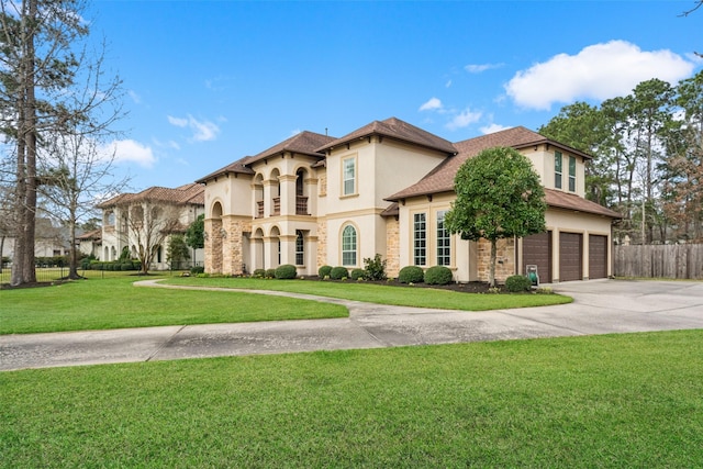 mediterranean / spanish home with a garage, fence, driveway, stucco siding, and a front yard