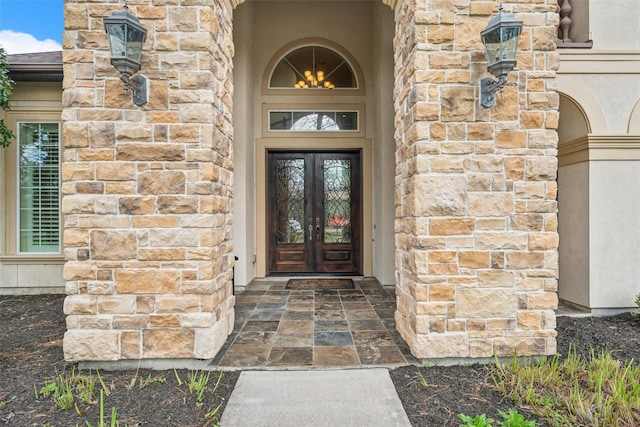 view of exterior entry with stone siding, french doors, and stucco siding