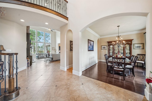 dining room featuring a towering ceiling, baseboards, arched walkways, and crown molding