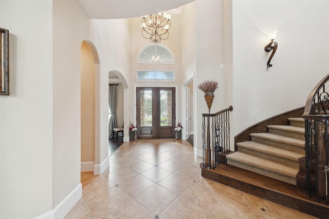 entrance foyer with light tile patterned floors, stairway, a high ceiling, an inviting chandelier, and baseboards