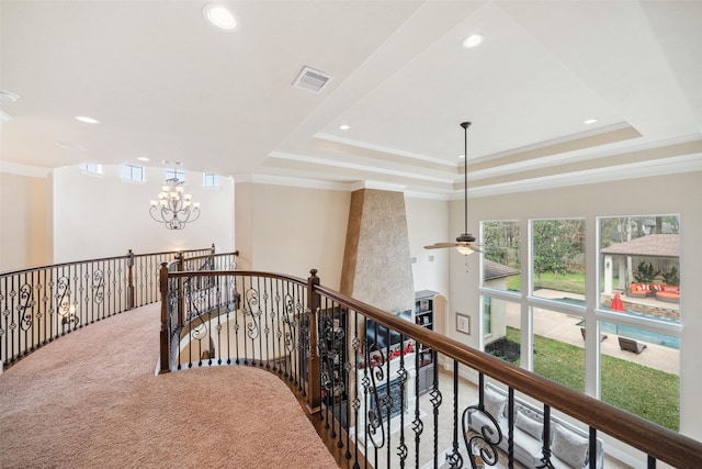 hall featuring visible vents, a tray ceiling, carpet flooring, an upstairs landing, and a notable chandelier