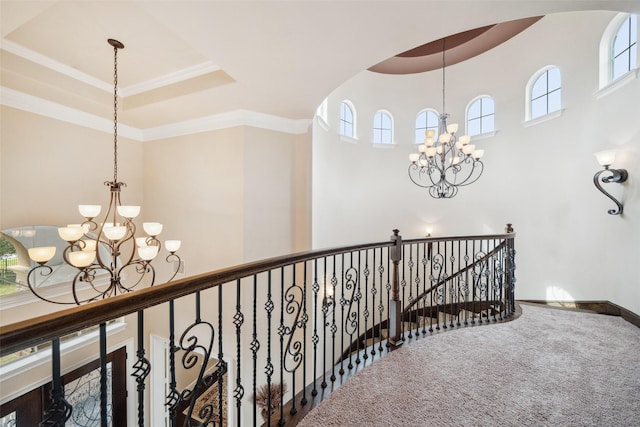 hallway with carpet, arched walkways, a raised ceiling, an inviting chandelier, and an upstairs landing