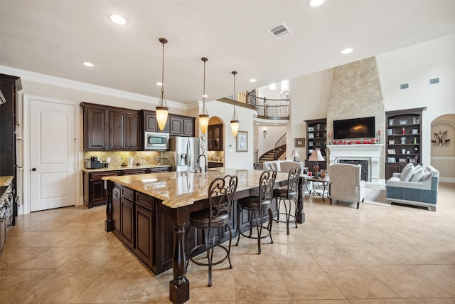 kitchen with dark brown cabinetry, visible vents, arched walkways, appliances with stainless steel finishes, and a fireplace