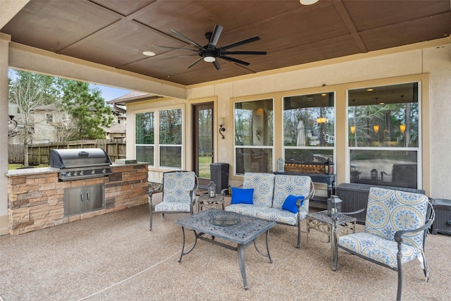 view of patio featuring ceiling fan, outdoor lounge area, fence, exterior kitchen, and grilling area