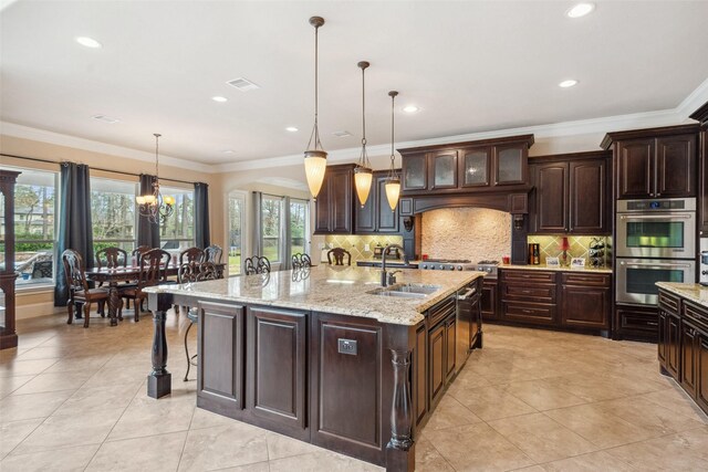 kitchen featuring decorative backsplash, crown molding, a large island with sink, double oven, and a sink