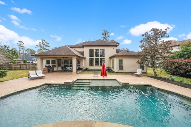 rear view of property featuring a patio, fence, a fenced in pool, and stucco siding