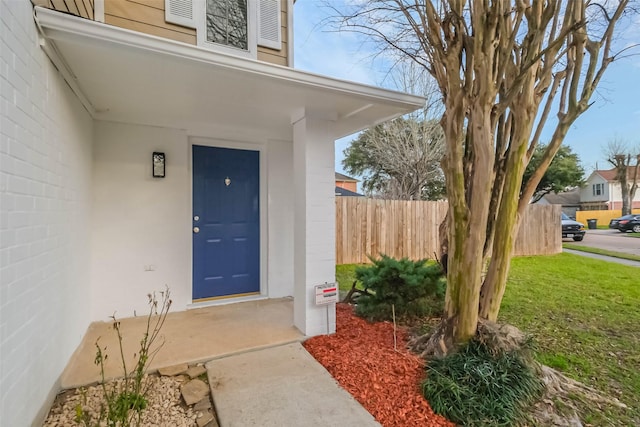 view of exterior entry featuring a yard and fence