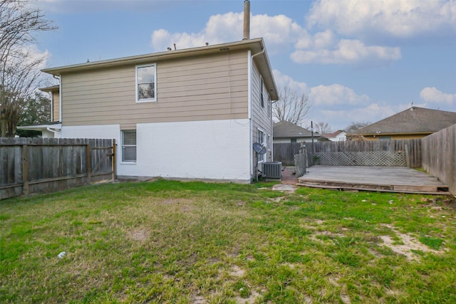 back of house featuring brick siding, a fenced backyard, a wooden deck, and a yard