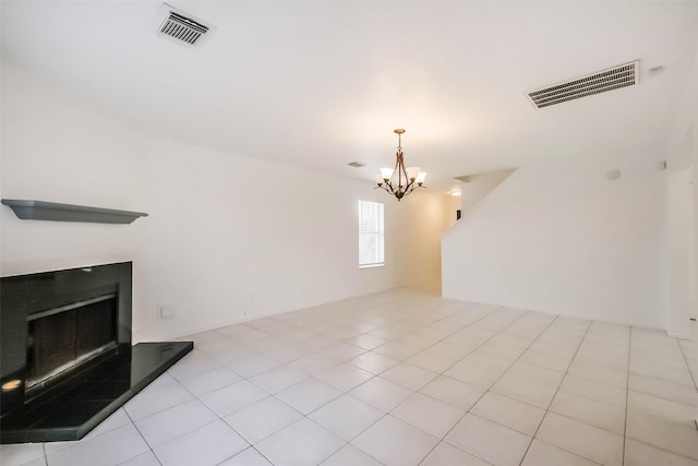 unfurnished living room featuring a chandelier, a fireplace with raised hearth, tile patterned flooring, and visible vents