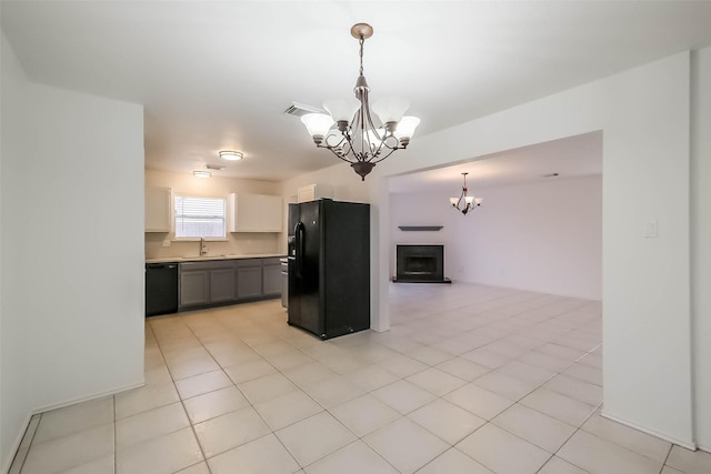 kitchen with a fireplace with raised hearth, an inviting chandelier, open floor plan, a sink, and black appliances