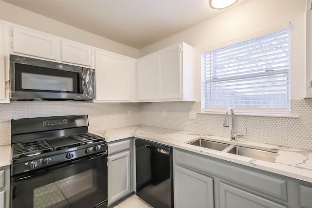 kitchen featuring black appliances, backsplash, a sink, and light stone countertops