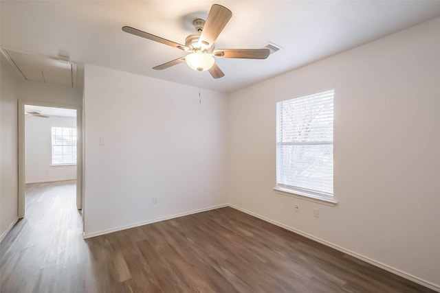 spare room with attic access, dark wood-type flooring, and baseboards