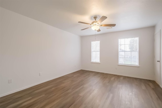 unfurnished room with ceiling fan, wood finished floors, and baseboards