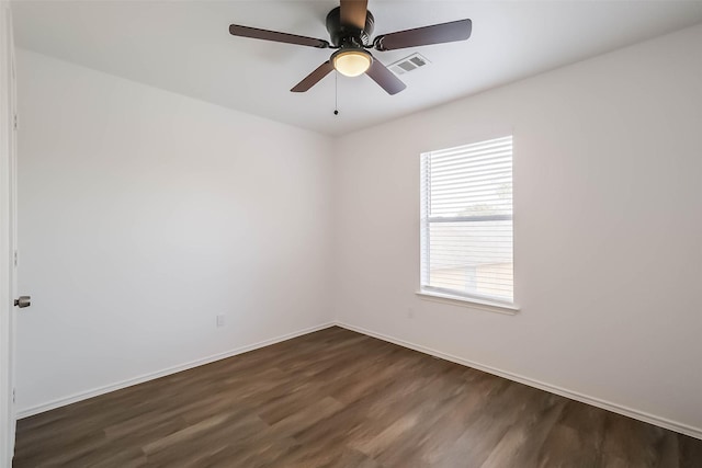 spare room with a ceiling fan, visible vents, dark wood finished floors, and baseboards