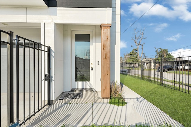 view of exterior entry featuring a yard and fence