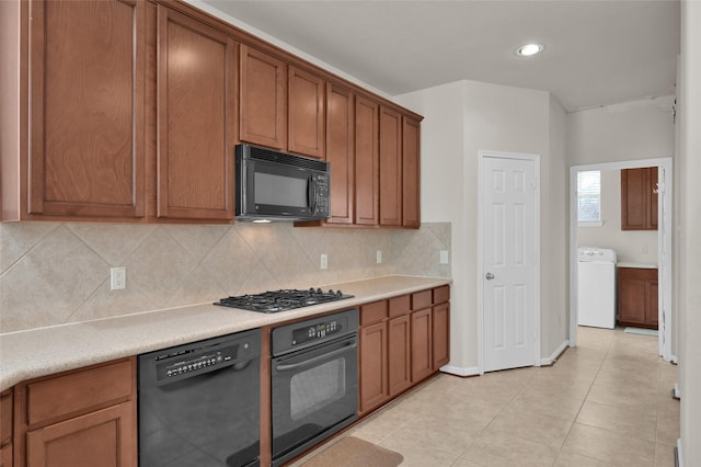 kitchen with black appliances, washer / clothes dryer, decorative backsplash, and light countertops