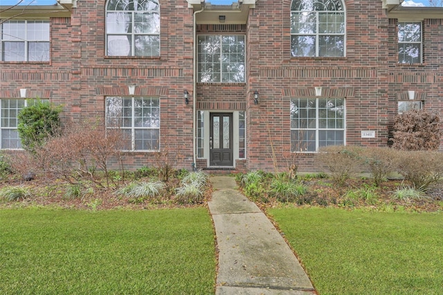 entrance to property with a lawn and brick siding