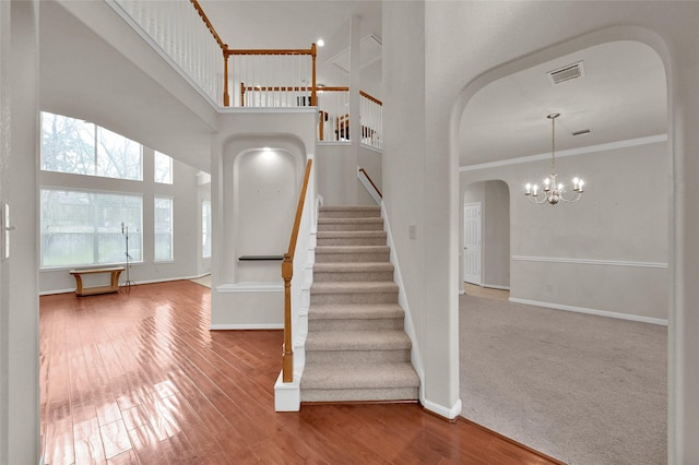 entrance foyer featuring arched walkways, wood finished floors, a towering ceiling, baseboards, and crown molding