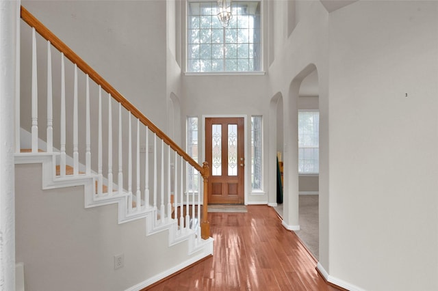 entryway with stairway, plenty of natural light, arched walkways, and wood finished floors