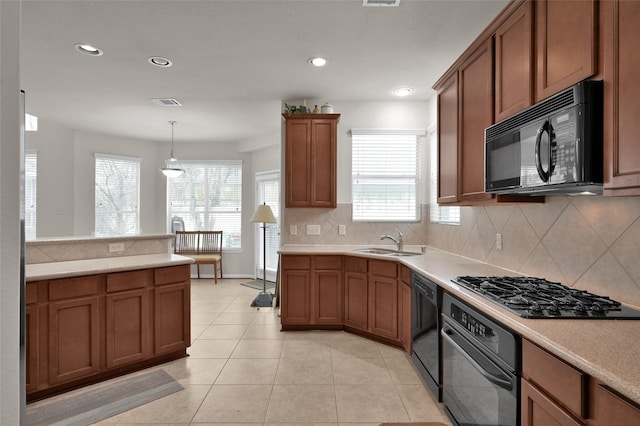 kitchen with a sink, light countertops, brown cabinets, decorative backsplash, and black appliances