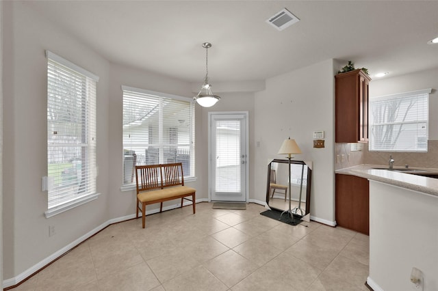 kitchen featuring light tile patterned floors, a sink, visible vents, light countertops, and tasteful backsplash