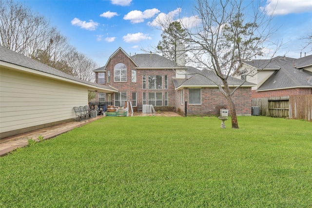 rear view of house featuring central AC unit, a yard, fence, and brick siding