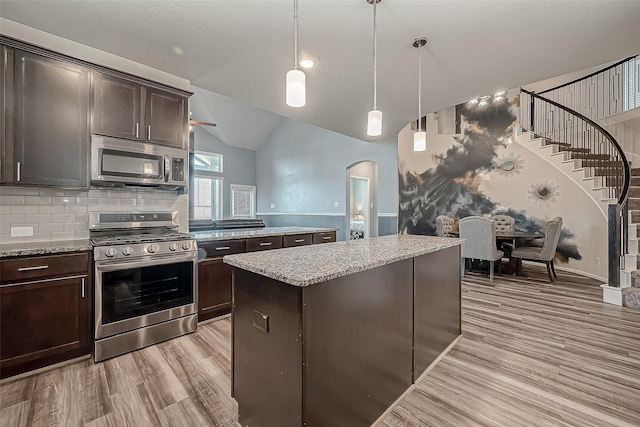 kitchen with stainless steel appliances, arched walkways, light wood-style flooring, and dark brown cabinets