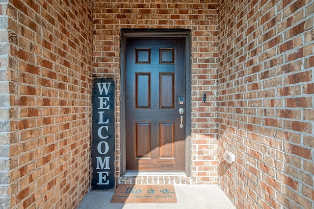 doorway to property featuring brick siding