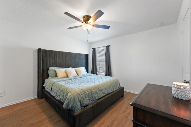 bedroom featuring ceiling fan, baseboards, and wood finished floors