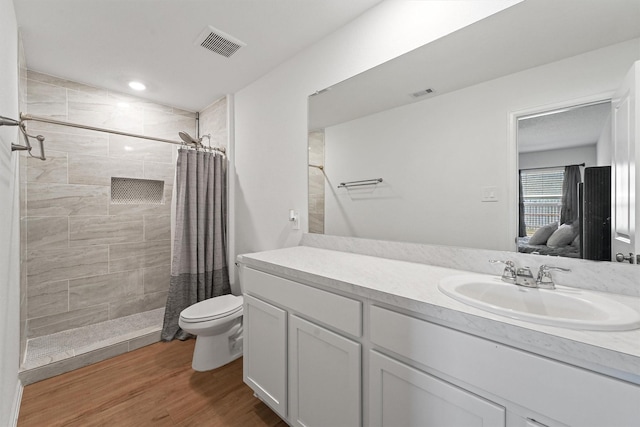 full bath with ensuite bathroom, toilet, wood finished floors, visible vents, and a tile shower