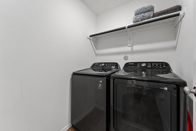 clothes washing area featuring laundry area, washer and clothes dryer, and baseboards