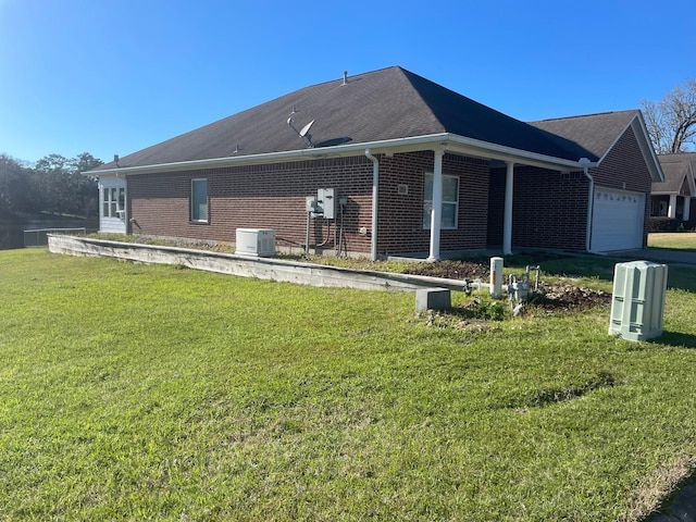 view of property exterior featuring a garage, a yard, brick siding, and central air condition unit