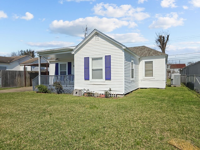 exterior space with a yard, roof with shingles, fence, and central air condition unit