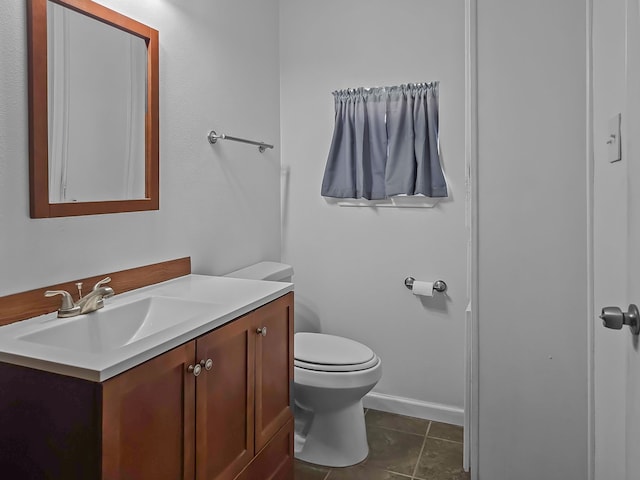 bathroom with toilet, baseboards, vanity, and tile patterned floors