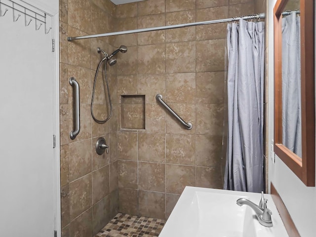 bathroom with a tile shower and a sink