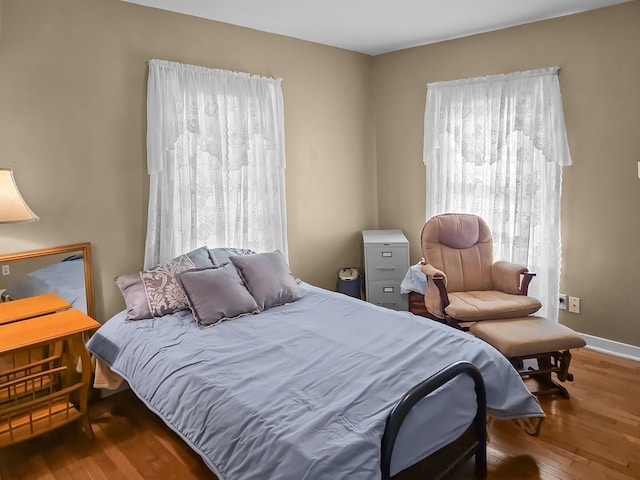 bedroom featuring multiple windows, wood finished floors, and baseboards