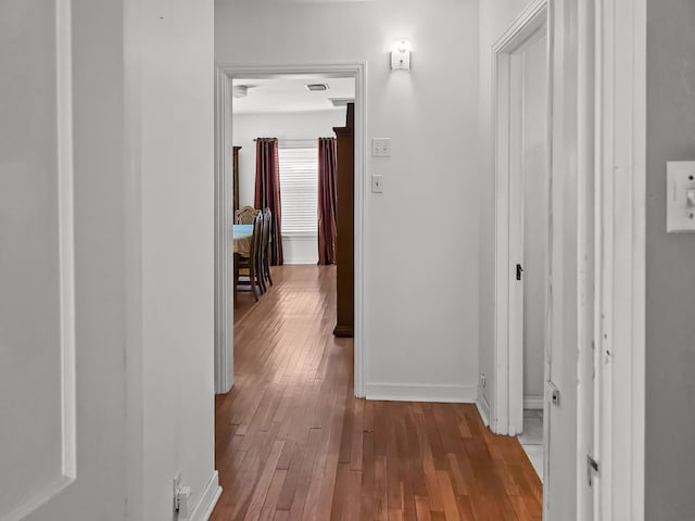 hallway featuring wood-type flooring, visible vents, and baseboards