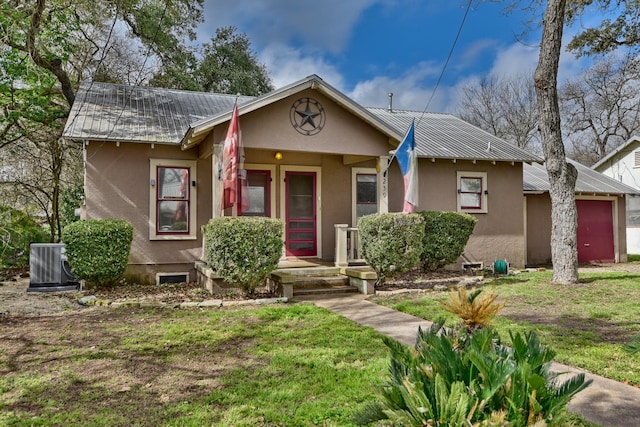 view of front of property with stucco siding, a front yard, metal roof, a garage, and cooling unit