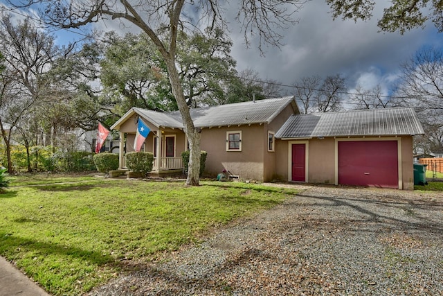 single story home with driveway, metal roof, an attached garage, a front yard, and stucco siding