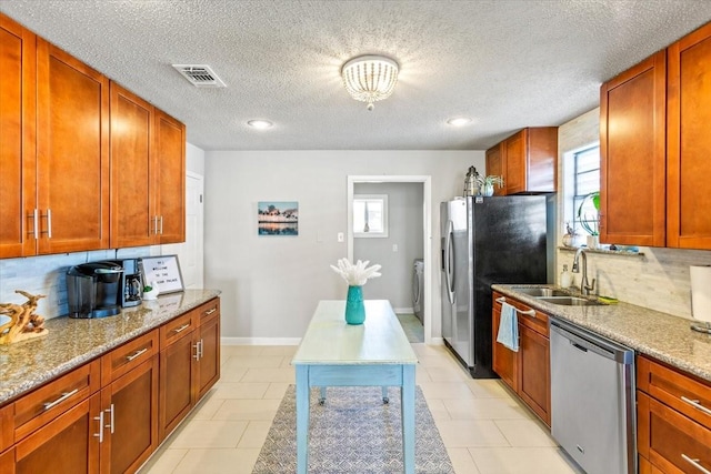 kitchen with light tile patterned floors, visible vents, decorative backsplash, appliances with stainless steel finishes, and washer / clothes dryer