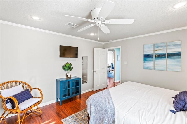 bedroom with a textured ceiling, ornamental molding, wood finished floors, and visible vents