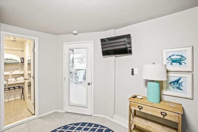 foyer entrance with light tile patterned floors, baseboards, and a textured ceiling