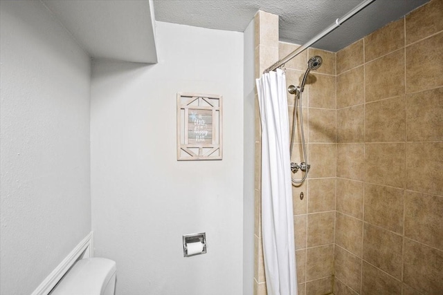 bathroom featuring toilet, a textured ceiling, and tiled shower